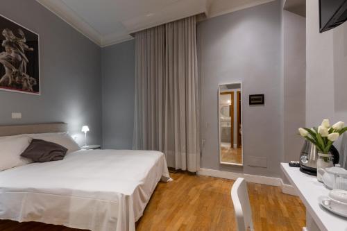 a bedroom with a white bed and a table and a mirror at River61 - Guest House in Rome