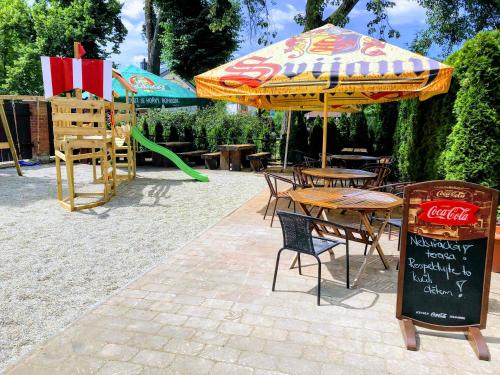 a table and chairs with an umbrella and a playground at Penzion Merlin in Frýdlant nad Ostravicí