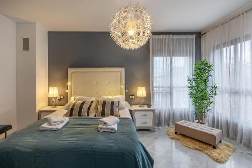 a bedroom with a large bed and a chandelier at Casa de Amigos La Latina con piscina, chimenea y barbacoa in Illora