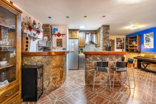 a kitchen with a bar and some stools at Casa de Amigos La Latina con piscina, chimenea y barbacoa in Illora