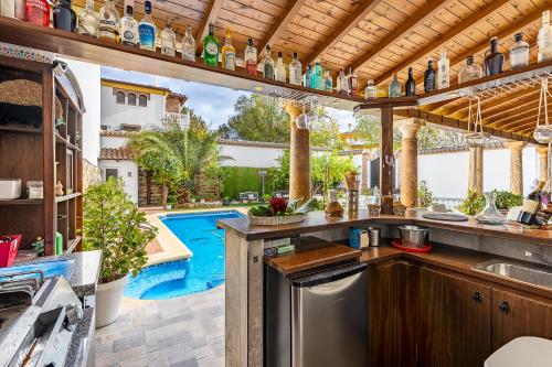 an outdoor kitchen with a pool in the background at Casa de Amigos La Latina con chimenea y barbacoa in Illora