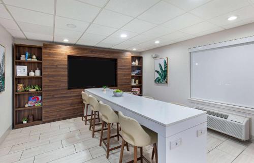 a large room with a bar with chairs and a flat screen tv at Wingate by Wyndham Hattiesburg in Hattiesburg