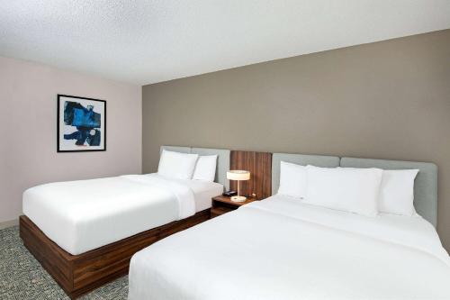 two beds in a hotel room with white sheets at Wingate by Wyndham Hattiesburg in Hattiesburg