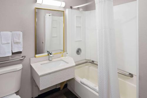 Days Inn & Suites by Wyndham Northwest Indianapolis في انديانابوليس: حمام مع حوض وحوض استحمام