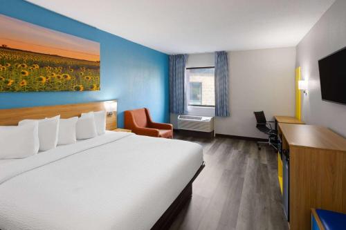 a hotel room with a bed and a desk and a window at Days Inn & Suites by Wyndham Northwest Indianapolis in Indianapolis