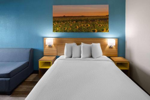 a bedroom with a bed and a blue couch at Days Inn & Suites by Wyndham Northwest Indianapolis in Indianapolis