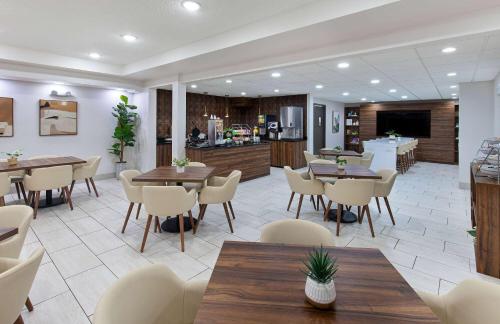 a restaurant with tables and chairs and a kitchen at Wingate by Wyndham Hattiesburg in Hattiesburg