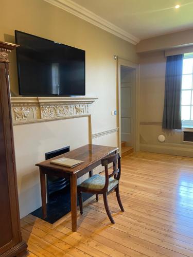 a room with a table and a television on a wall at Holbrook Manor & Spa in Wincanton