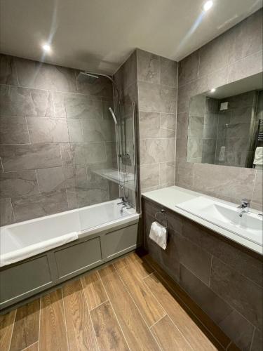 a bathroom with a tub and a sink and a bath tub at Holbrook Manor & Spa in Wincanton