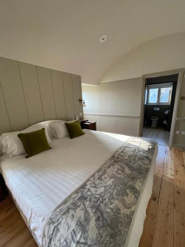 a bedroom with a large white bed with green pillows at Holbrook Manor & Spa in Wincanton