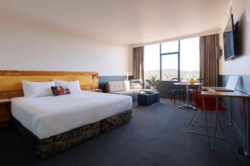 a hotel room with a large bed and a desk at Atura Albury in Albury