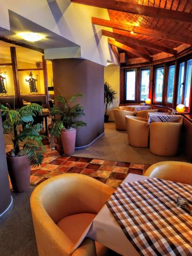 un restaurante con sofás y plantas en una habitación en Penzion Merlin, en Frýdlant nad Ostravicí