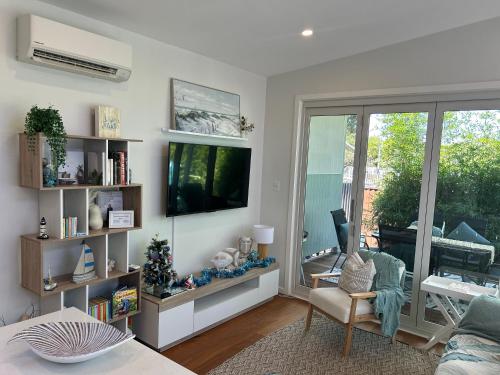 a living room with a television and a couch and a chair at Woonona Family Beach Villa 5 min walk to beach in Woonona