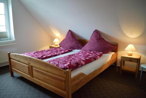 a bedroom with a wooden bed with purple pillows at Uthlande in Dagebüll