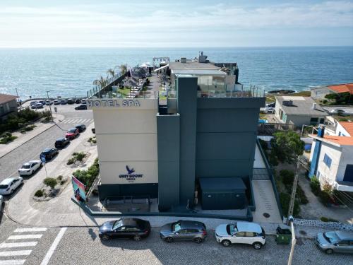 a hotel with cars parked in a parking lot next to the ocean at Hotel Mar e Sol & Spa in São Pedro de Moel