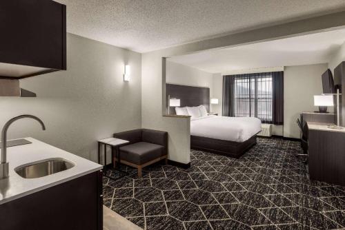 a hotel room with a bed and a chair and a sink at La Quinta Inn & Suites by Wyndham Lake George in Lake George