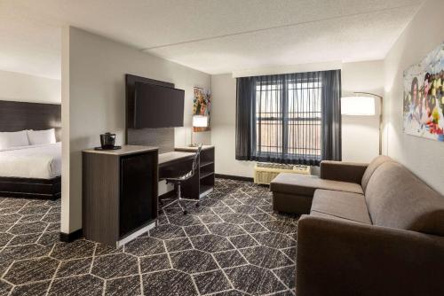 a hotel room with a bed and a couch and a desk at La Quinta Inn & Suites by Wyndham Lake George in Lake George