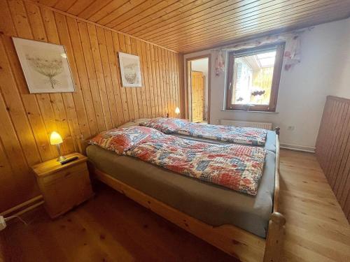 1 dormitorio con 1 cama en una pared de madera en Bellos Ferienbungalow, Hunde willkommen, Sauna, WLAN, eingezäunt, Strandkorb, Zwinger, 