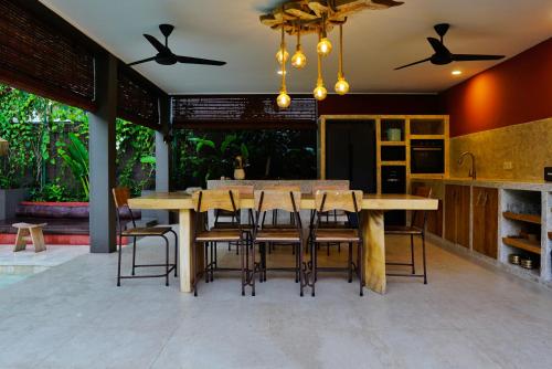 a dining room with a large wooden table and chairs at Lasai Villas in Gili Air