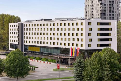 a large white building with a parking lot in front of it at Vienna House Easy by Wyndham Katowice in Katowice