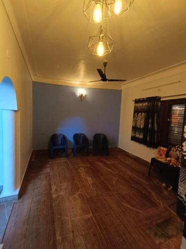 an empty living room with two blue chairs and a ceiling at Agnisthala Guest House in Tiruvannāmalai