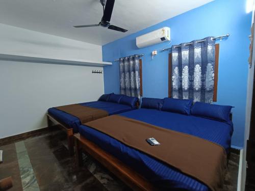 a bedroom with two beds and a blue wall at Agnisthala Guest House in Tiruvannāmalai