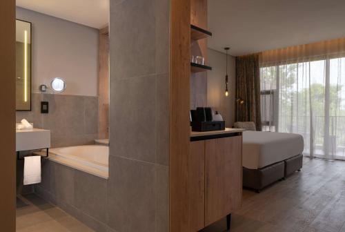 a bedroom with a bed and a bath tub and a sink at Radisson Safari Hotel Hoedspruit in Hoedspruit