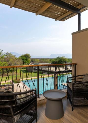 a balcony with a table and chairs and a pool at Radisson Safari Hotel Hoedspruit in Hoedspruit