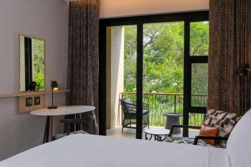 a bedroom with a bed and a balcony at Radisson Safari Hotel Hoedspruit in Hoedspruit
