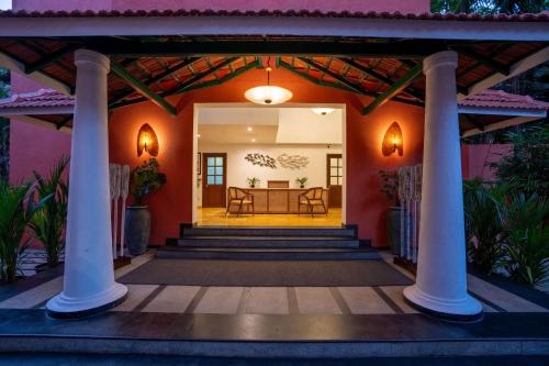 a home with a porch with columns and a table at Mandrem Beach Resort, a member of Radisson Individuals Retreat in Mandrem