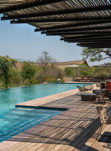 a swimming pool with tables and chairs next to a swimming pool at Radisson Safari Hotel Hoedspruit in Hoedspruit