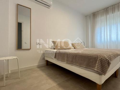 a white bedroom with a bed and a mirror at Moderno apartamento a pocos metros de la playa 126A - INMO22 in Cambrils