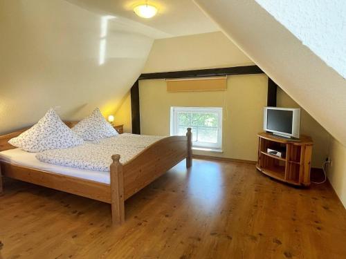 een slaapkamer met een bed en een televisie op zolder bij Haus Benninghusumer Deichweg, eingezäunt, Hunde Willkommen, Kamin, ruhig gelegen, WLAN in Emmelsbüll-Horsbüll