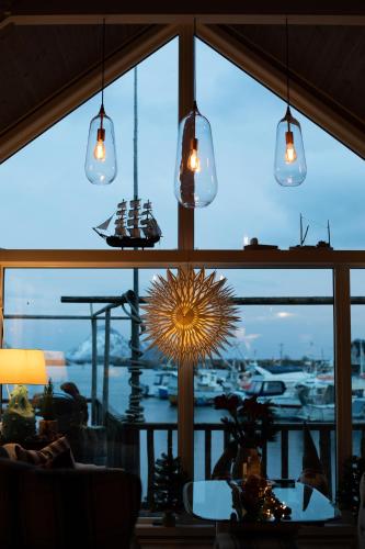 a room with a large window with a table and lights at Kræmmervika Havn in Ballstad