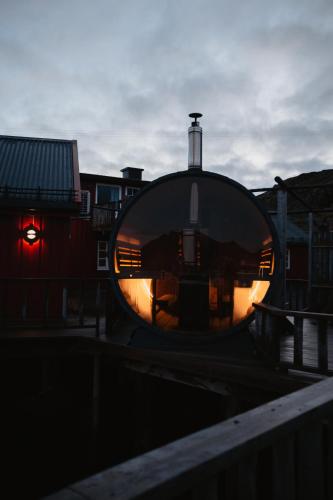 a round building with a reflection of a building at Kræmmervika Havn in Ballstad