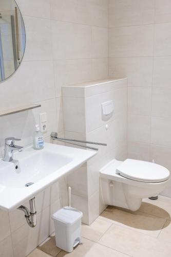 a white bathroom with a toilet and a sink at Ferienwohnung Tide 21 in Norddeich