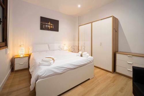 a bedroom with a white bed and a cabinet at Asturches Apartamento in Gijón