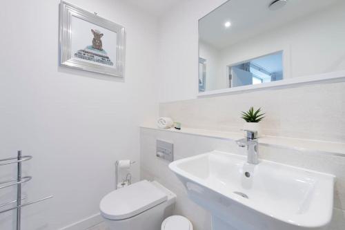 a white bathroom with a sink and a toilet at Finsbury Park Penthouse: Luxe City Living in London