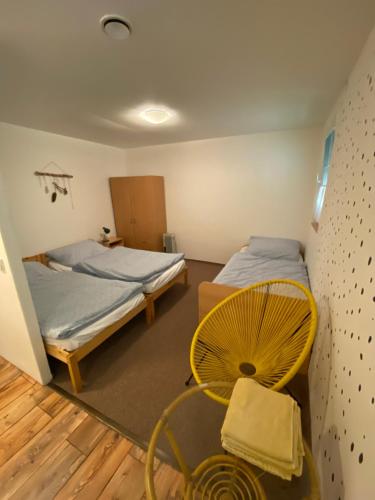 1 dormitorio con 2 camas y silla amarilla en Chata Trojanovice, en Trojanovice