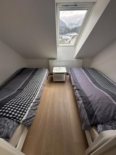 2 Betten in einem kleinen Zimmer mit Fenster in der Unterkunft De luxe Apartment GOLOB Kranjska Gora in Kranjska Gora