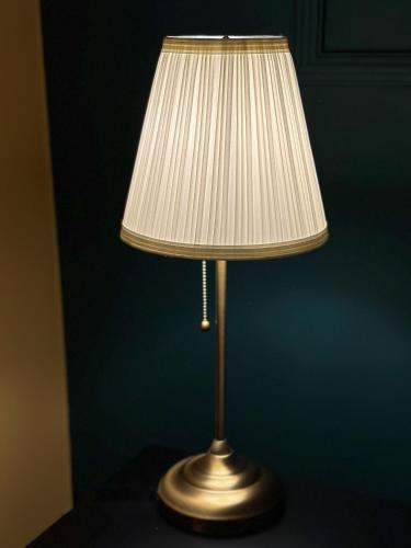 a gold lamp with a white lamp shade on a table at Hotel Cocó in Timişoara