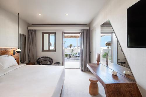 ein Hotelzimmer mit einem Bett und einem Schreibtisch mit Aussicht in der Unterkunft Noūs Santorini in Mesariá