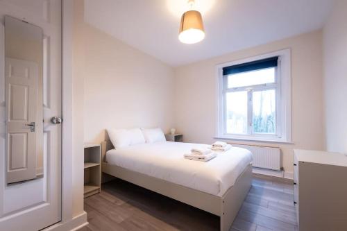 um quarto branco com uma cama branca e uma janela em Comfy - 3 Bedroom Flat With Parking em Southampton