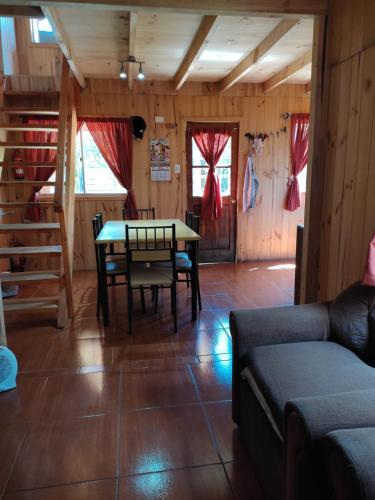 a living room with a table and chairs and a couch at cabaña de 2 pisos in Coñaripe