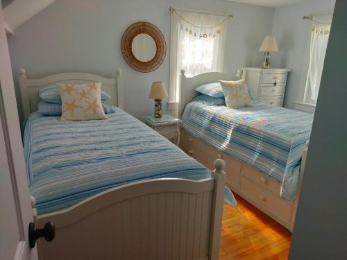 a bedroom with two beds and a mirror on the wall at Sandtrap Cape Cod in West Yarmouth