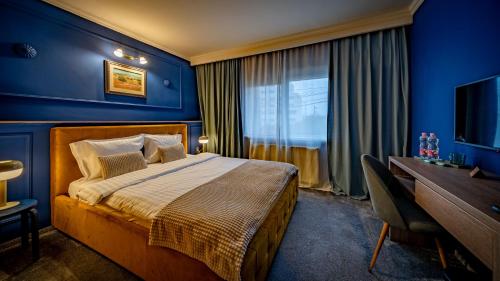 um quarto com paredes azuis, uma cama e uma secretária em Hotel Cocó em Timişoara