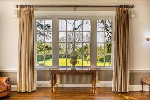 ein Wohnzimmer mit einem großen Fenster und einem Tisch in der Unterkunft Holbrook Manor & Spa - OCEANA COLLECTION in Wincanton