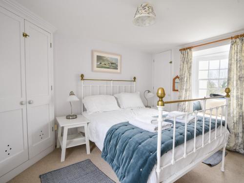 een witte slaapkamer met een bed en een raam bij Lyme Regis Cottage in Lyme Regis