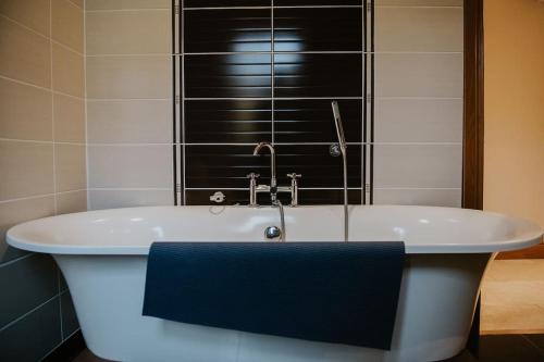 La salle de bains est pourvue d'une baignoire et d'une serviette bleue. dans l'établissement Seoidín House, à Gweedore