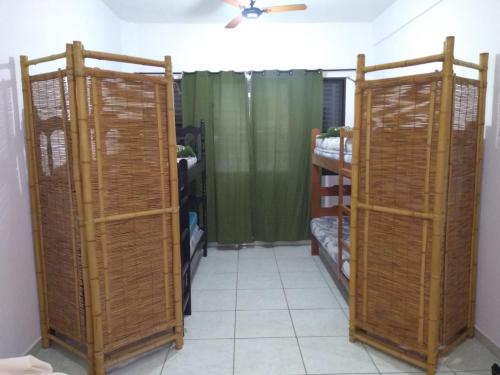a room with three wicker shelves and a green curtain at Pé na areia in Mongaguá